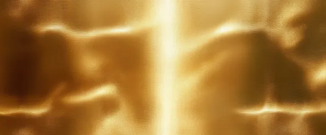 Close-up of a polished gold metal surface with reflective highlights and shadowed ridges.