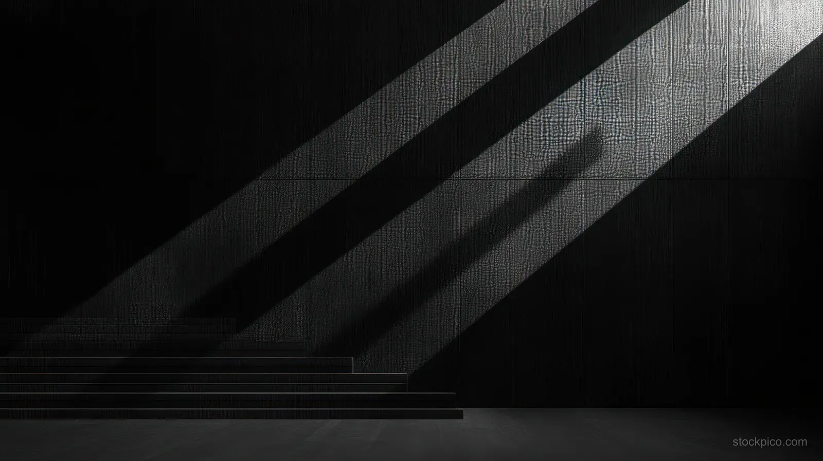 Dark staircase in an empty interior with linear shadows from angled light beams across a textured wall.