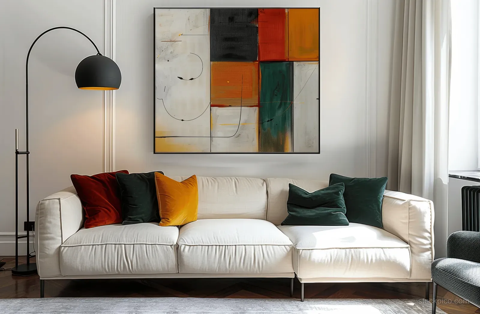 White sofa with colorful cushions beneath abstract wall art and a black floor lamp beside a window curtain.
