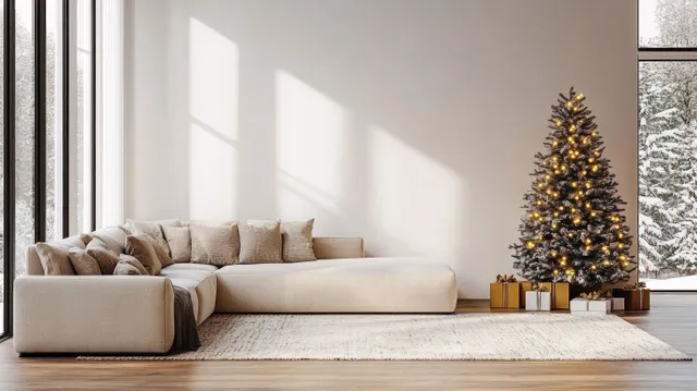 A lit Christmas tree stands by a sunlit window in a minimalist living room with a beige sofa and rug.