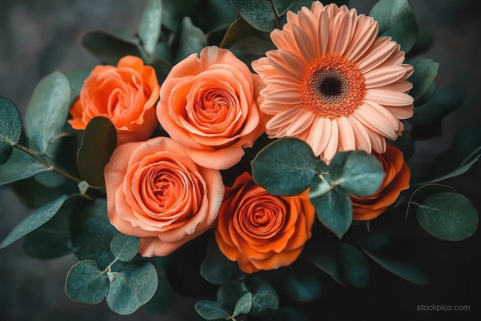 Orange roses and a peach gerbera daisy surrounded by eucalyptus leaves in a close-up floral arrangement.
