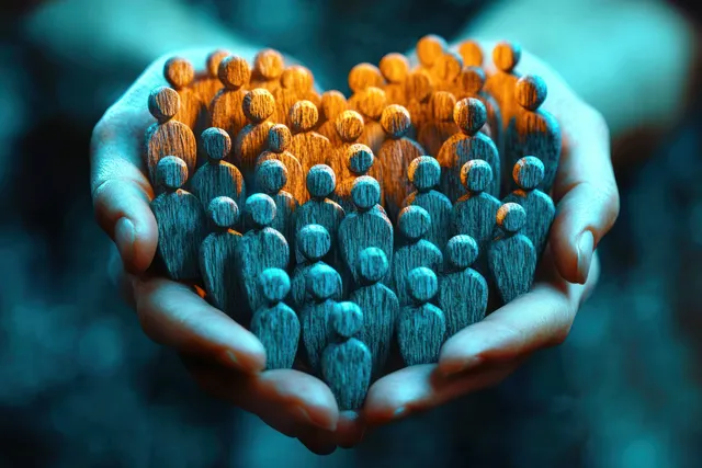 Two hands holding a heart of wooden figurines with warm orange and blue glow