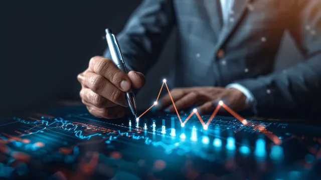 Analyst hand draws an upward finance chart over a glowing blue data grid on a dark screen.
