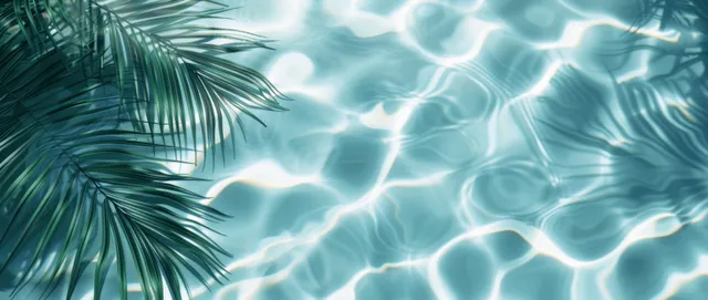 Top view of turquoise pool water with palm leaf shadows on sandy beach ripple patterns