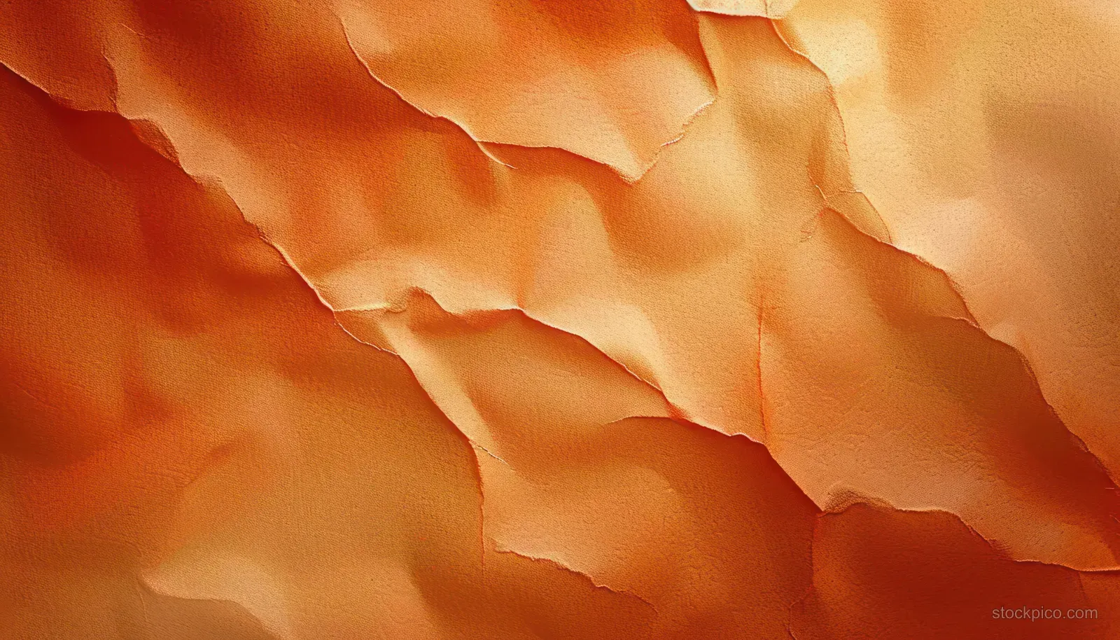Close-up of torn orange paper layers with rough texture and soft shadowed folds.