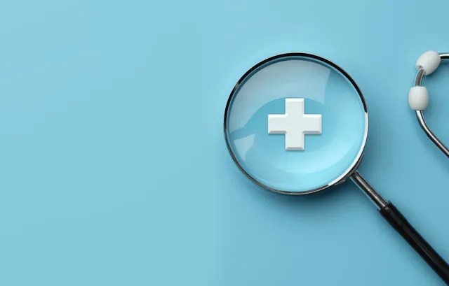 3D magnifying glass highlighting a white plus medical cross on blue background