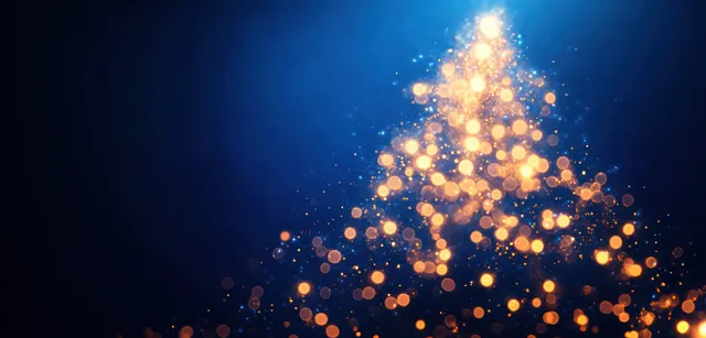 A softly focused glowing Christmas tree made of golden bokeh lights on a deep blue night background.