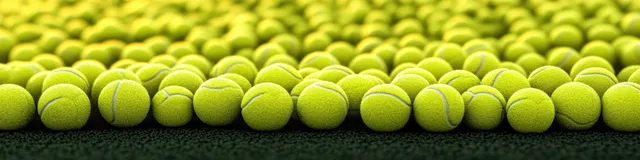 A close-up row of yellow tennis balls with textured felt, rim lighting, and dark shadows.