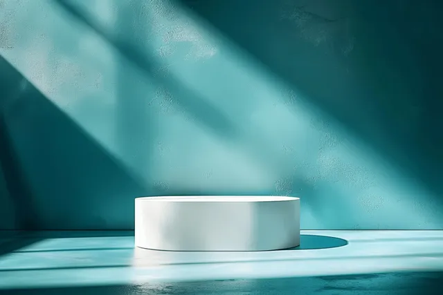 White rectangular block on a teal surface with soft studio light and abstract shadows.