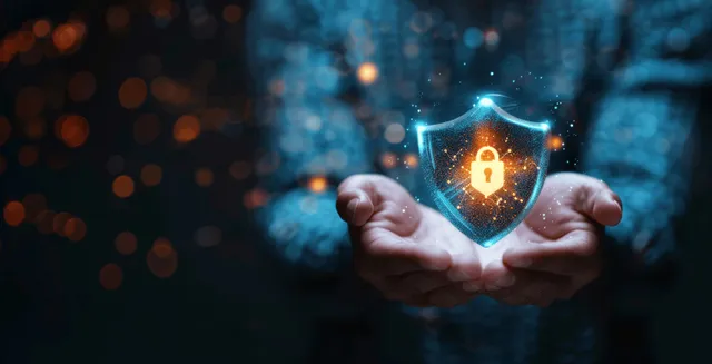 Hands hold a glowing shield with a lock over a blurred blue digital background.