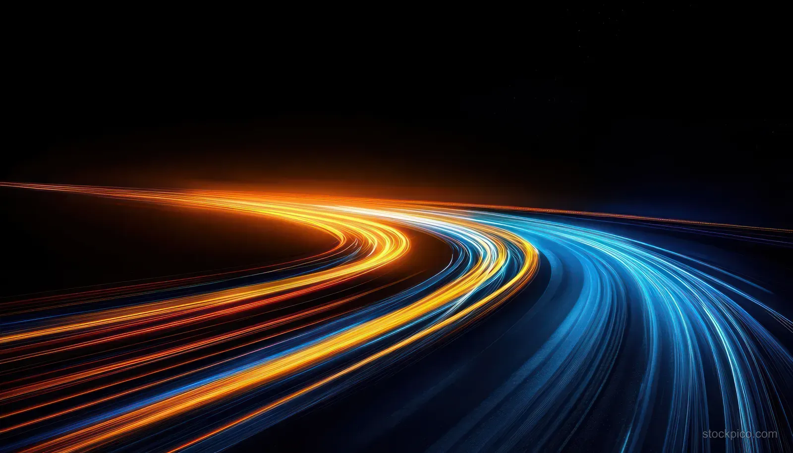 Curving night highway shows long-exposure blue and orange light trails stretching across dark asphalt.