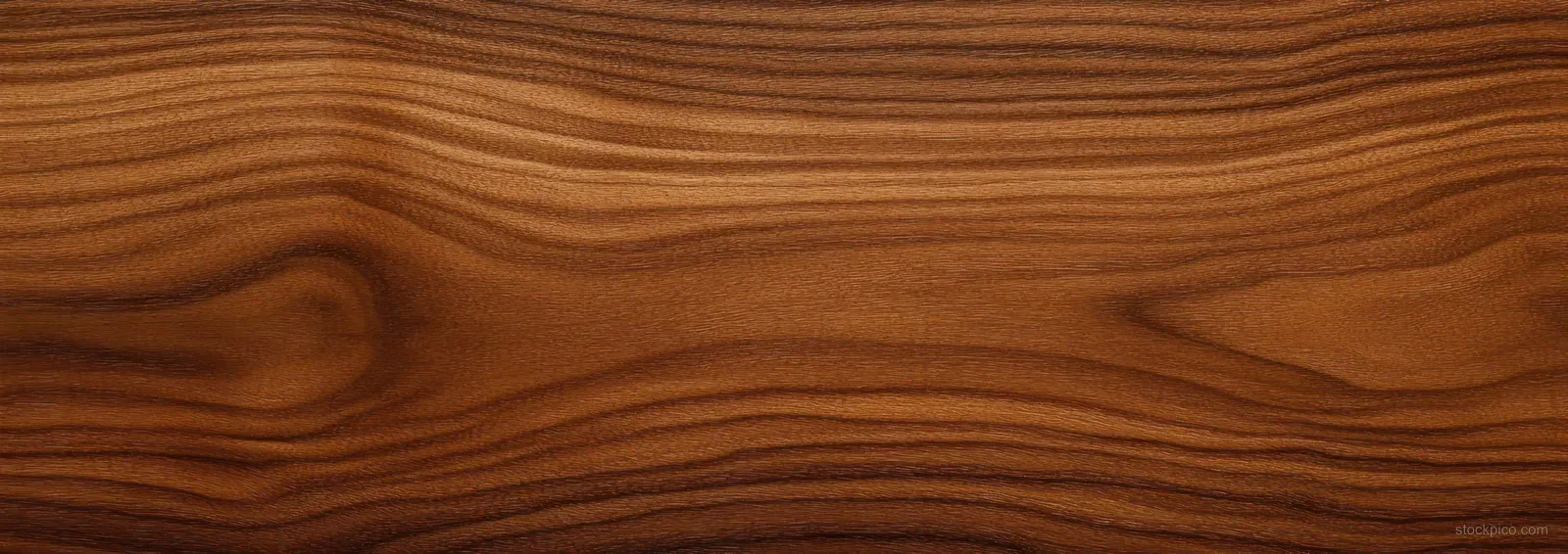 Smooth brown wooden surface close-up with natural wavy grain lines and warm tones.