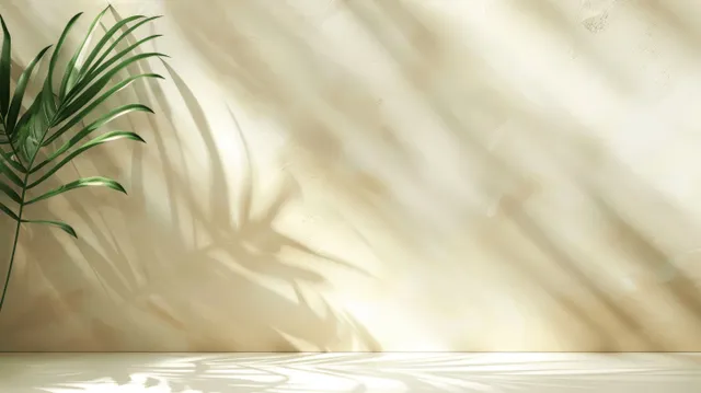 Abstract palm leaf shadows on a light cream wall create a soft, minimal background with ample copy space.