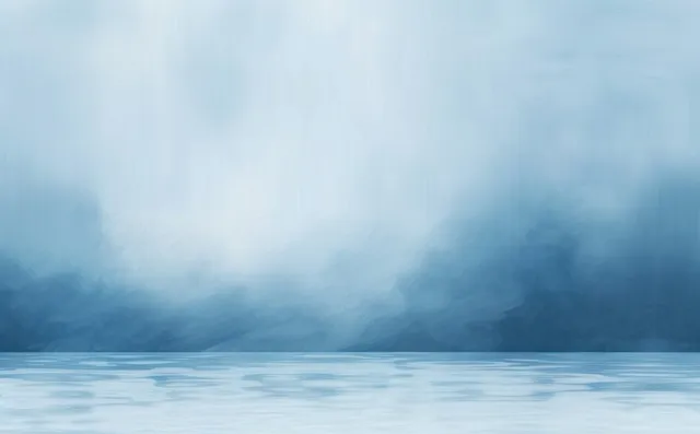 Calm water surface reflecting a misty blue sky with soft layered clouds