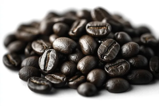 Shiny dark roasted coffee beans piled on a clean white background in a close-up view.