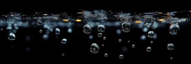Air bubbles rising through dark water, forming small spheres with sparkling reflections and subtle surface ripples.