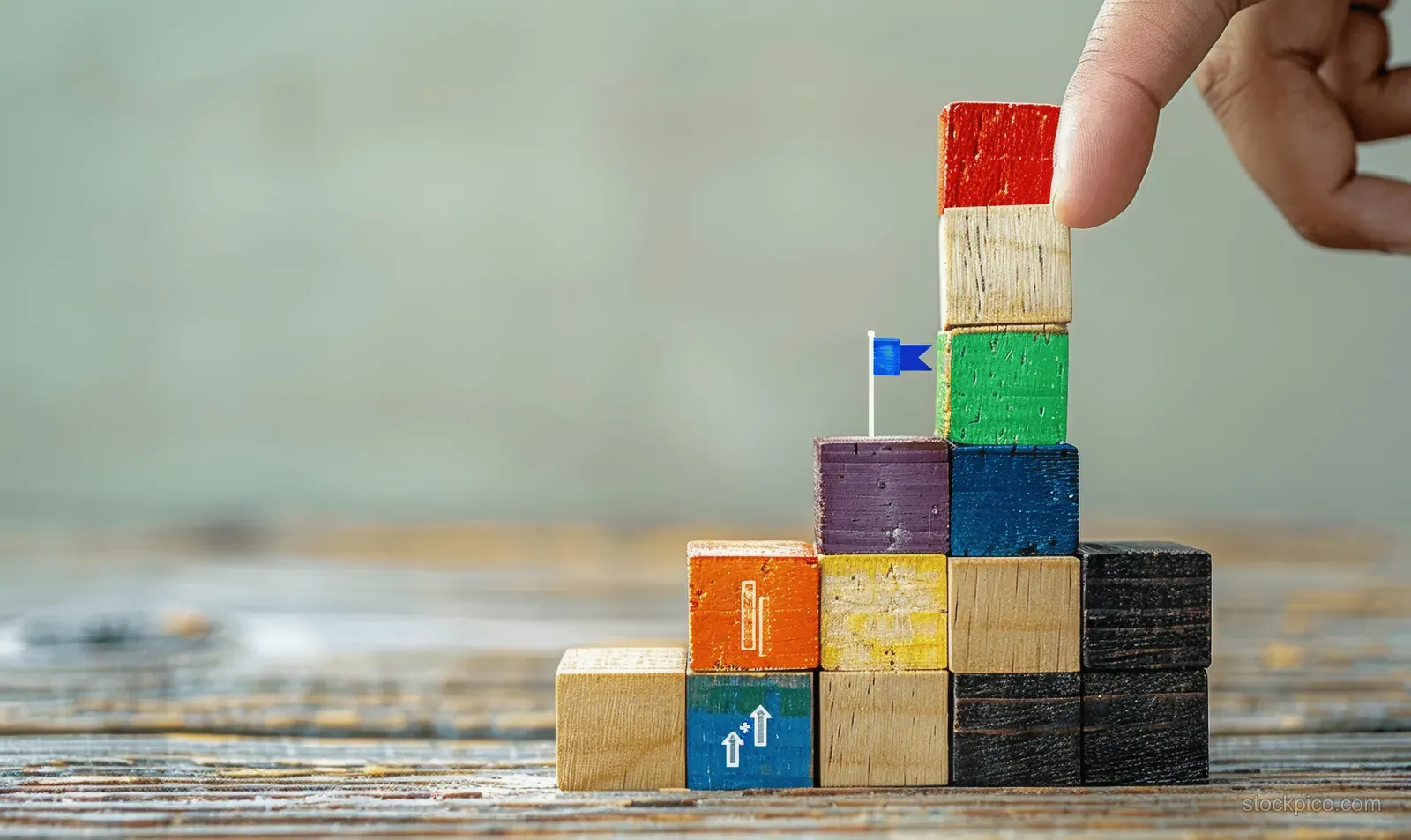 A hand stacks colorful wooden blocks into a stepped timeline on a tabletop.