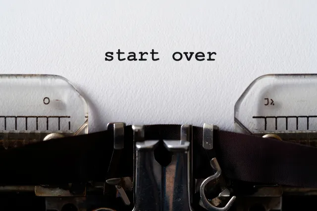 An old typewriter types the words “start over” onto white paper in a close-up view.