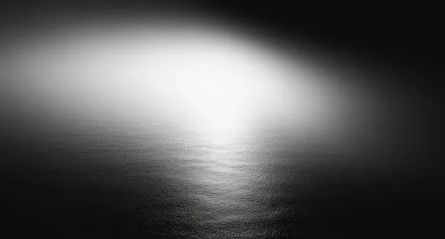Monochrome abstract background with a soft white glow fading into black and a subtle grain texture.