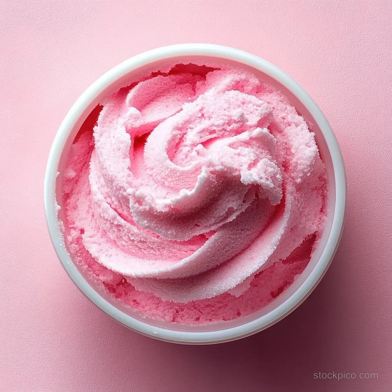 Pink sugar scrub with a swirled cream texture in a small white bowl on a pastel pink background.