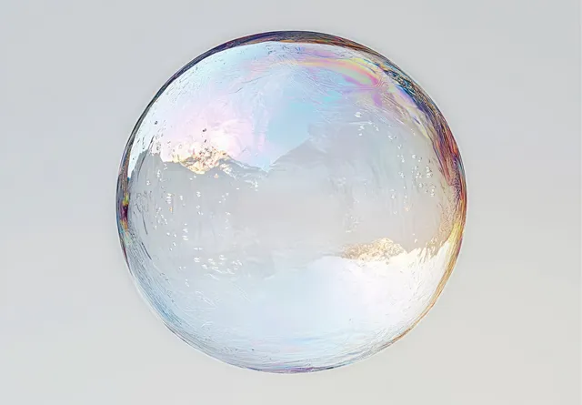 A translucent soap bubble floats against a plain light background, shimmering with iridescent rainbow colors.
