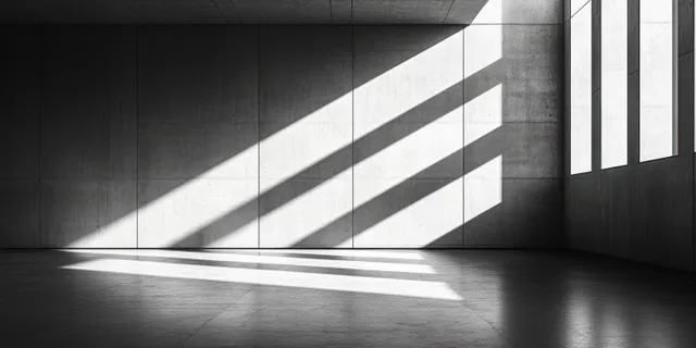 Minimalist concrete interior room with sunbeams cutting across geometric walls and casting sharp shadow bands on the floor.
