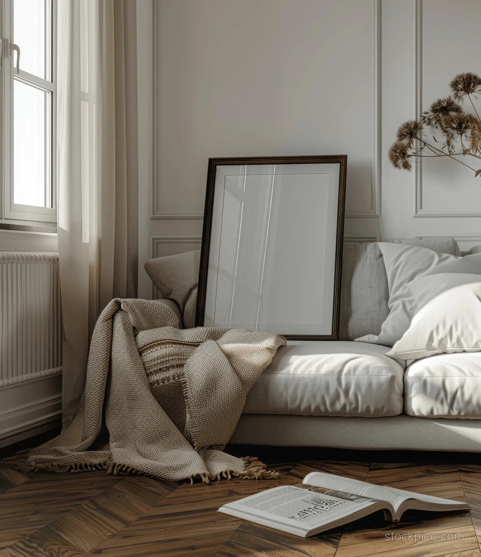 Neutral living room with sofa and a blank A4 frame mockup beside an open book on the floor.