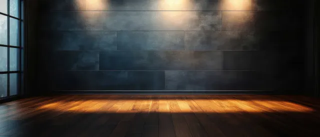 Empty modern interior room with dark textured wall, warm ceiling spotlights, and wooden floor under window light.