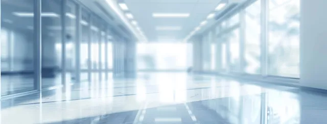 Blurred light blue office corridor with panoramic windows, reflective floor, and soft ceiling lighting.