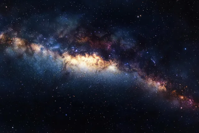 The Milky Way band shines through a dense star field with dark dust lanes and bright stellar clusters in deep space.