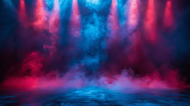 Blue and red spotlights illuminate drifting stage smoke over an empty dark auditorium floor.