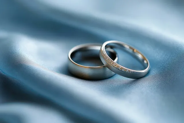 Two silver wedding rings resting on blue satin, soft glow and delicate reflections
