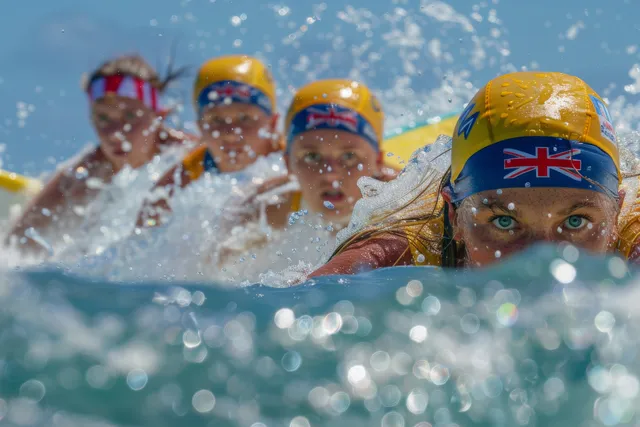 Female surfers sprint into the surf during a shortboard semifinal with splashing waves