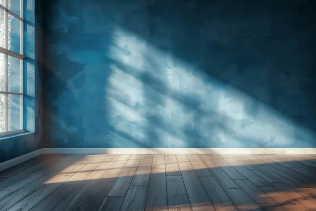 Sunlit empty room with turquoise wall, wooden floor, and window-cast shadows forming streaks.