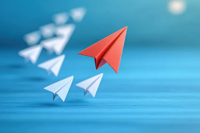 A red paper airplane leads multiple white paper planes across a blue gradient sky background.