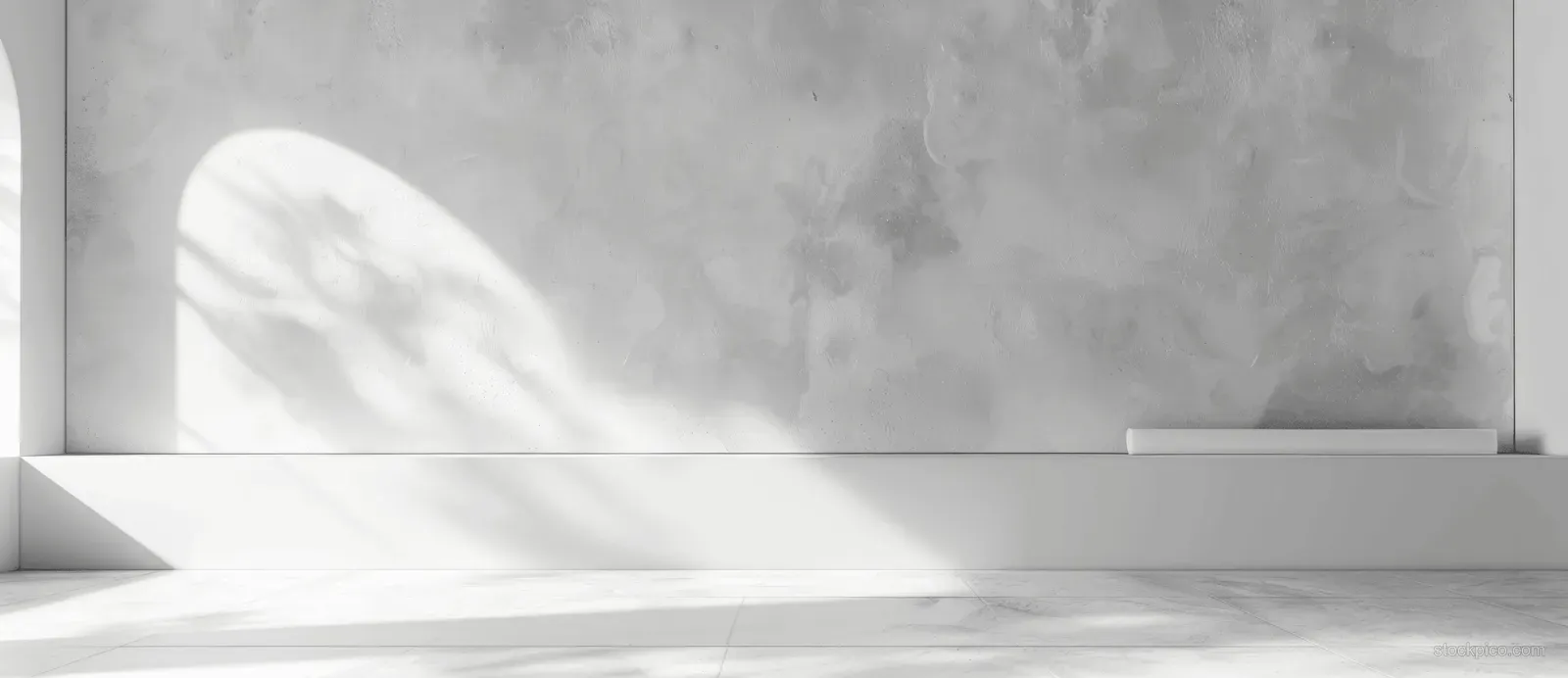 White pedestal and stepped platform on a gray plaster wall with soft light creating gentle shadows and empty display space.