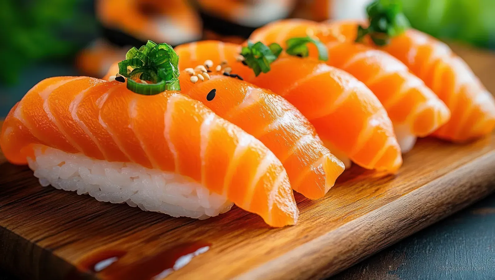 Salmon nigiri sushi on a wooden board with green onion garnish and sesame seeds in close-up.