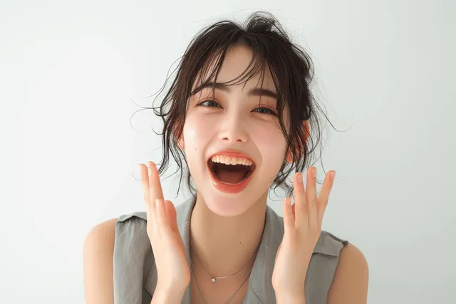 Cheering Japanese businesswoman with open-mouth smile and raised hands on plain white background